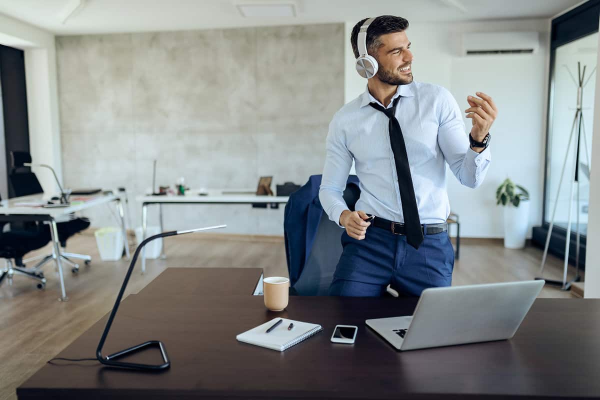 Happy entrepreneur taking a break from work and having fun while listening music over headphones in the office.