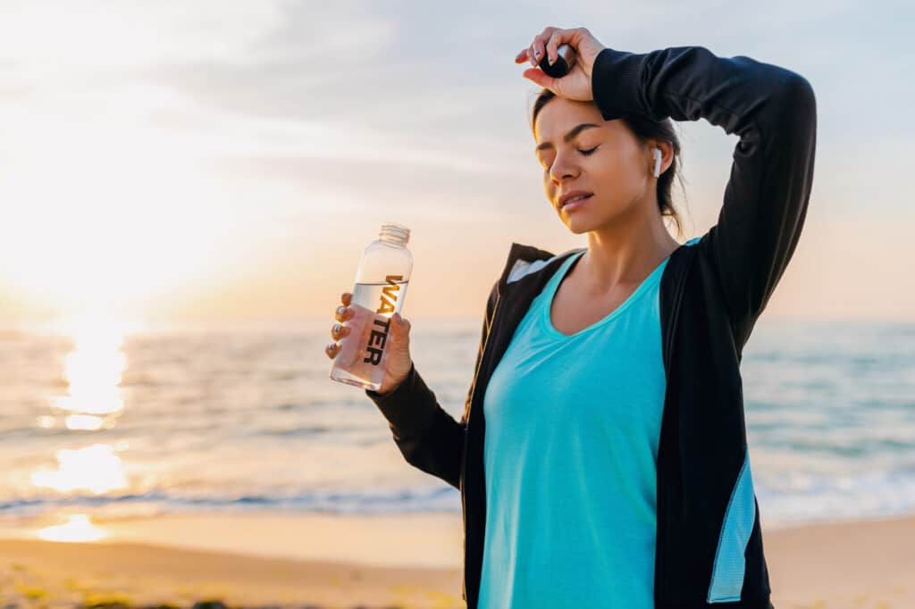 Attractive Slim Woman Doing Sport Exercises Morning Sunrise Beach Sports Wear Thirsty Drinking Water Bottle Healthy Lifestyle Listening Music Wireless Earphones Hot Summer Day